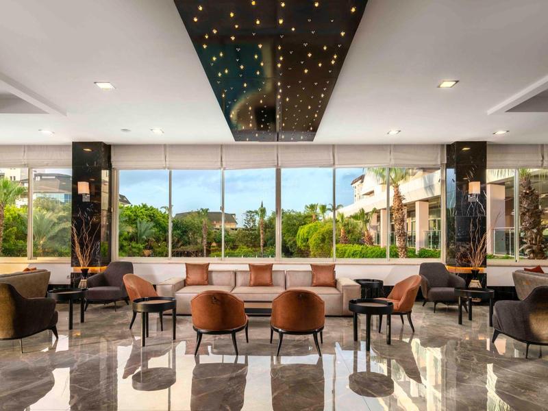 Hall d'hôtel lumineux avec grandes fenêtres, mobilier moderne et sol en marbre