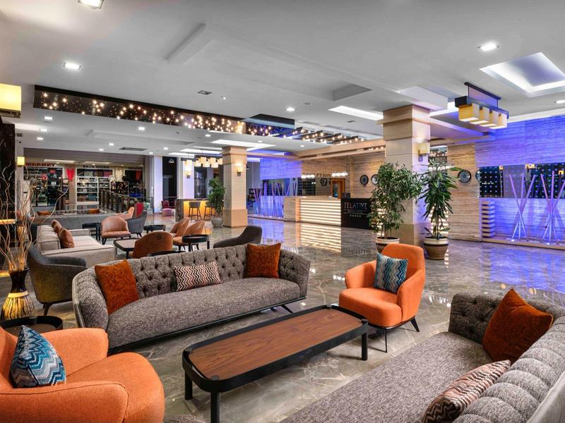 Hall d'hôtel moderne avec sièges confortables, tapis et éclairage élégant.