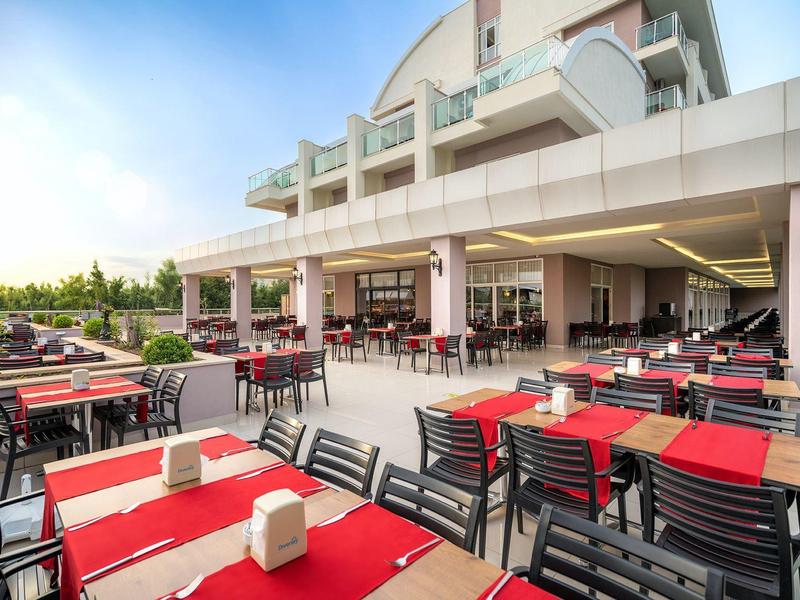 Terrasse extérieure moderne d'un hôtel avec tables et chaises en journée.