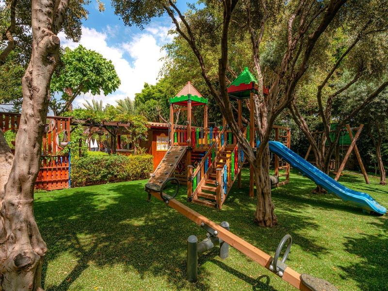 Aire de jeux colorée avec toboggans, balançoires et structures d'escalade dans un espace vert.