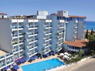 Grande edificio dell'hotel con più balconi e piscina all'aperto vicino al mare.