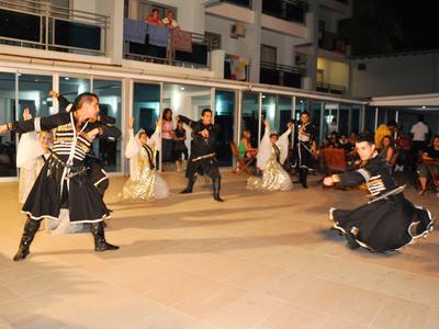 Actuación de danza tradicional con hombres en trajes frente a un edificio iluminado por la noche.