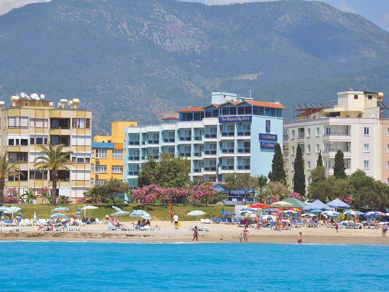 Spiaggia con lettini davanti a hotel e montagne sullo sfondo