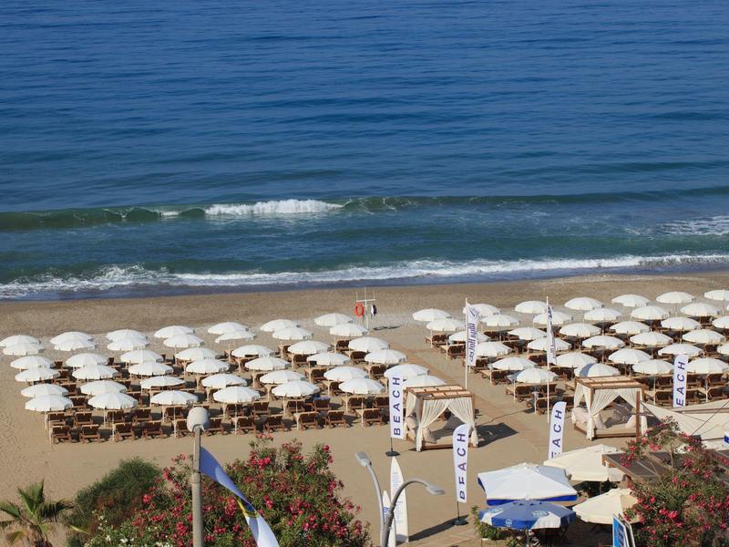Vista di una spiaggia con file di ombrelloni bianchi e lettini vicino all'acqua.
