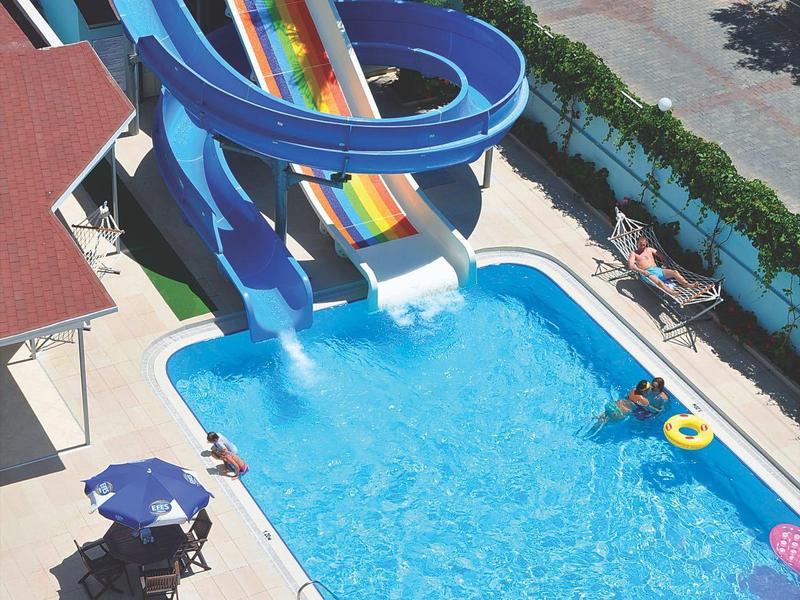 Parco acquatico con scivoli d'acqua blu, piscina e ombrelloni in una giornata di sole