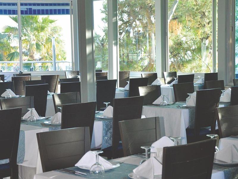 Ristorante elegante con tovaglie bianche e blu e vista sul verde.