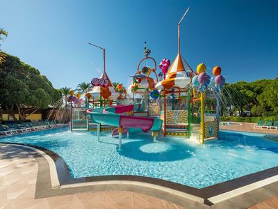 Barevné vodní hřiště s tobogány a vodními atrakcemi v bazénu pod čistou oblohou.