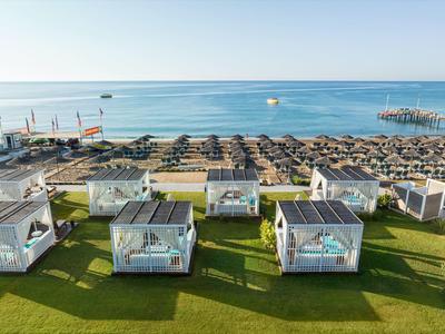 Pohled na pláž s deštníky a bílými lounžovými kabinovými postelemi u moře.