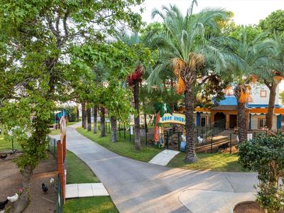 Dlážděná cesta procházející tropickou vegetací vedoucí k hotelu s barevnými detaily.