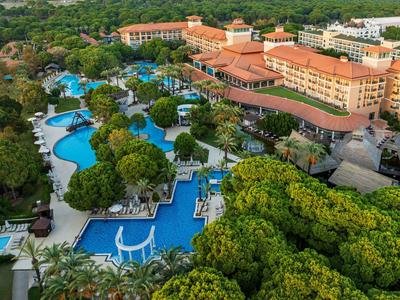 Letecký pohled na resort s několika bazény obklopenými tropickými stromy a velkými budovami.