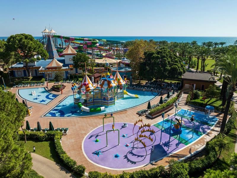 Barevný vodní a zábavní park u moře se skluzavkami, bazény a venkovními hřišti.