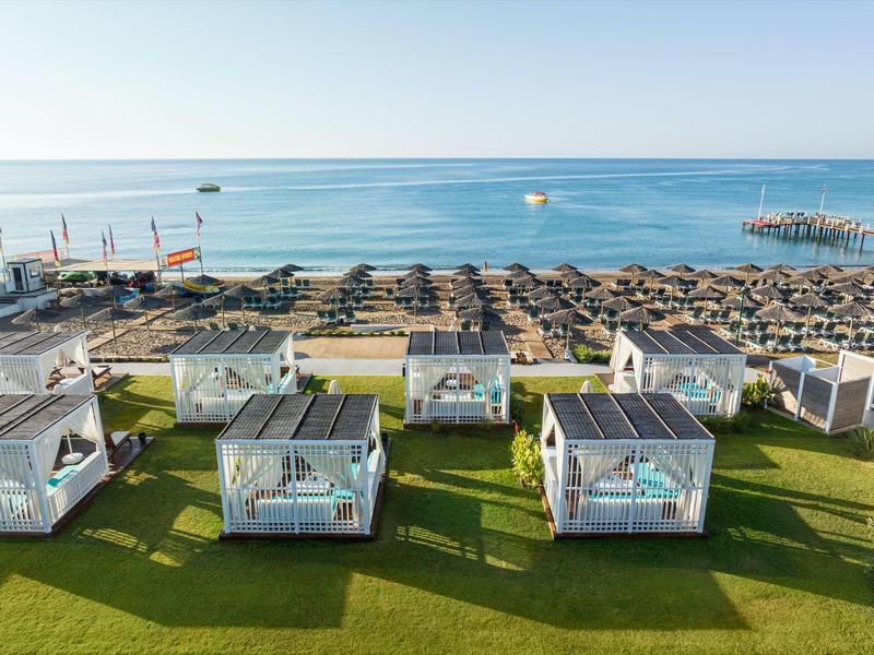 Pohled na pláž s deštníky a bílými lounžovými kabinovými postelemi u moře.