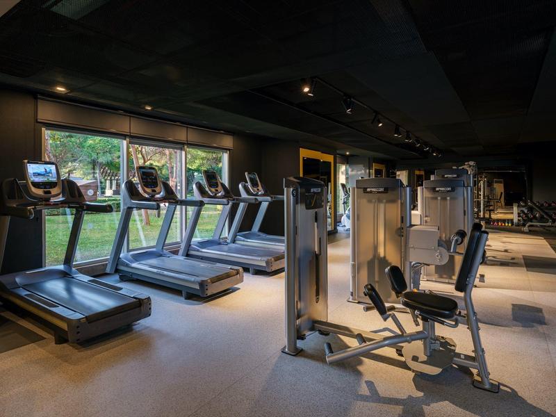 Moderní fitness vybavení v dobře osvětlené tělocvičně s velkými okny.