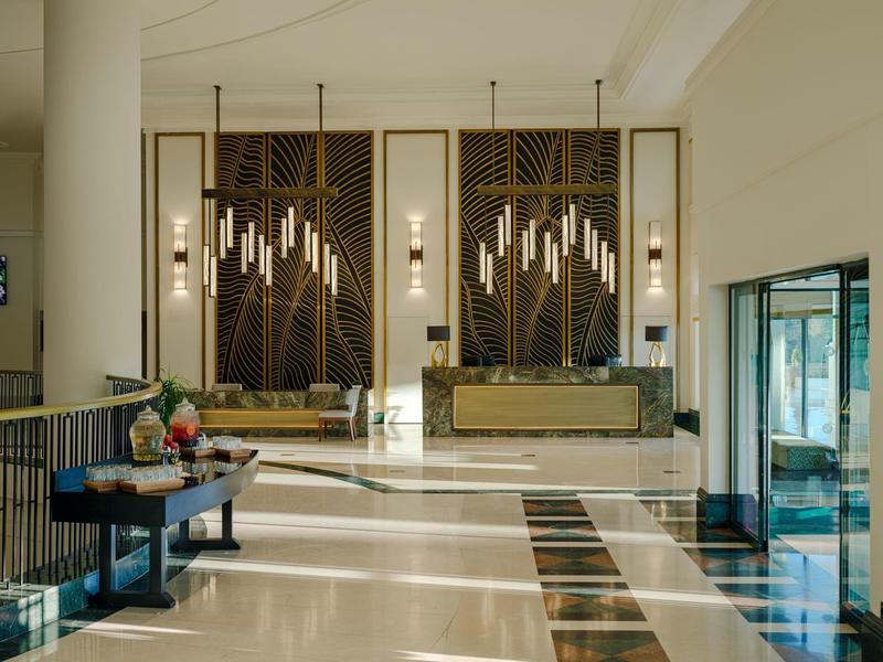 Elegantní hotelová lobby s moderním osvětlením a mramorovou podlahou.