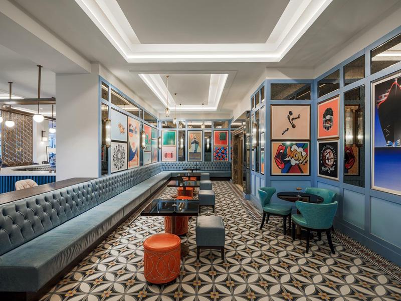 Moderní hotelová posezení s čalouněnými lavicemi, barevnými stoličkami a dekorativními stěnami.