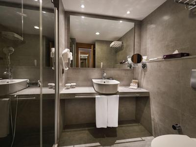 Modernes Badezimmer mit grauen Wänden, Glasdusche, Waschbecken auf Konsole und Handtüchern darunter.