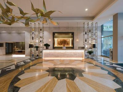Moderne Hotellobby mit hellem Marmorboden, gepolsterter Rezeption und Glaswänden.