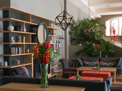 Modern eingerichtetes Wohnzimmer mit Holzregalen, Sofa, roten Kissen und großer grüner Pflanze.