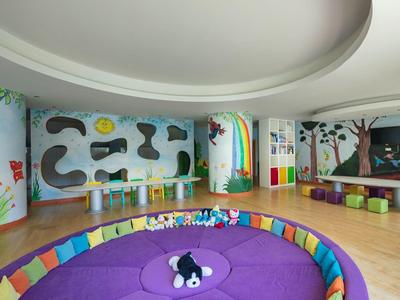 Ein Raum mit bunten Sitzkissen, einer Wandbemalung mit Regenbogen und Tiermotiven.
