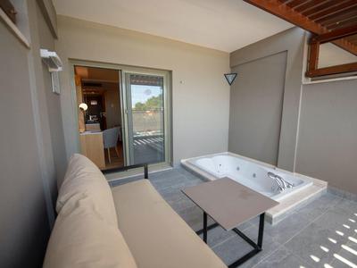 Moderner Balkon mit grauer Wand, eingebautem Whirlpool, Sofa und kleinem Tisch.