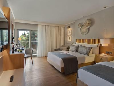Modernes Hotelzimmer mit zwei Betten, Holzboden, großem Fenster und neutralen Farbtönen.