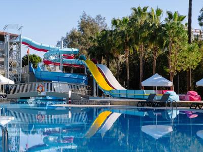 Ein türkisblauer Wasserpark mit Wasserrutschen, Palmen und klarem Wasser im Schwimmbecken.