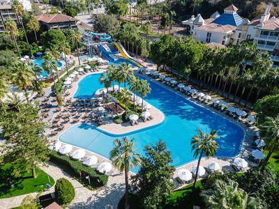 Groot buitenzwembad met glijbanen, palmbomen en ligstoelen in een tropisch resort.