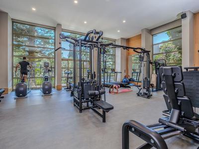 Nowoczesna siłownia z różnym sprzętem do ćwiczeń w hotelu z dużymi oknami.