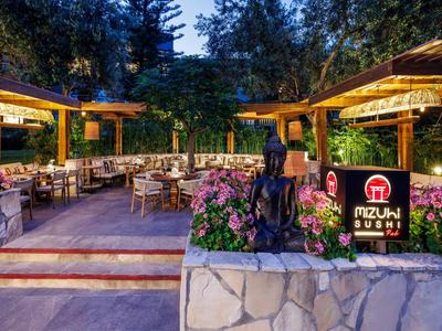 Wieczorny taras restauracji sushi z drewnianymi meblami i kwitnącymi roślinami