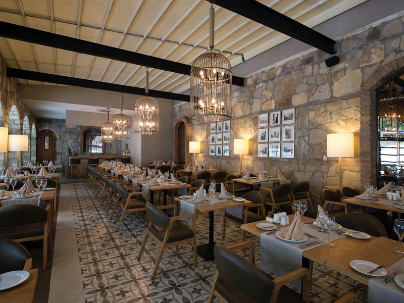 Ristorante elegante con pareti in pietra, lampadari e tavoli ben apparecchiati.