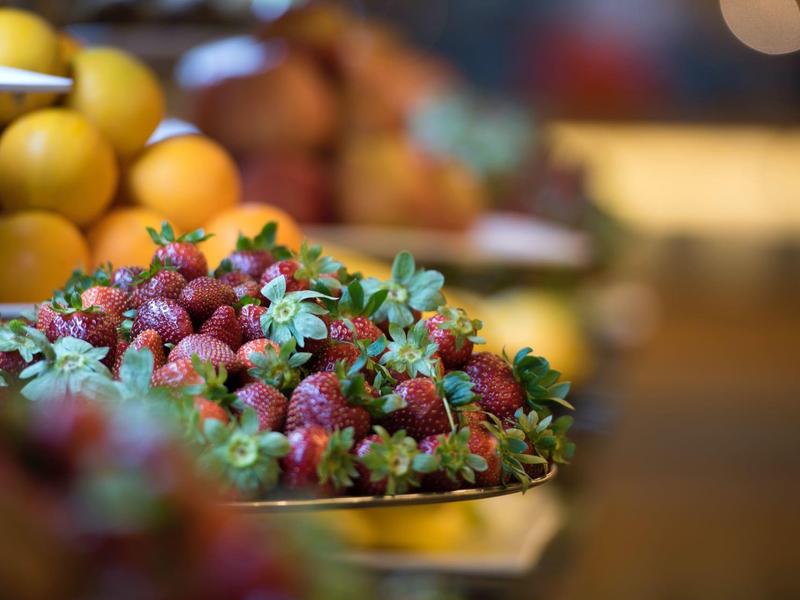 Primo piano di fragole fresche su una bancarella di mercato con sfondo sfocato.