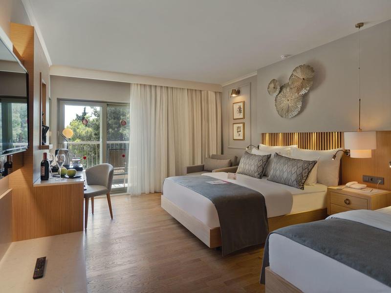 Stanza d'hotel moderna con due letti, grande finestra e pavimento in legno.