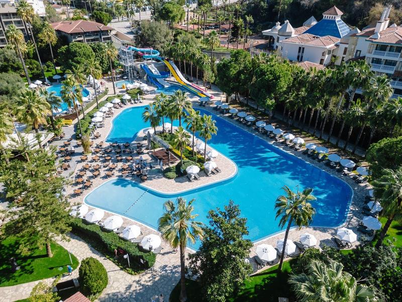 Grande piscina con lettini e palme in un complesso alberghiero sotto il sole