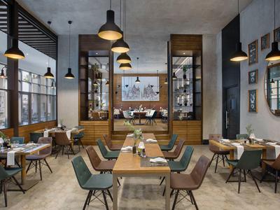 Ristorante moderno con tavoli in legno, sedie colorate e ampie finestre