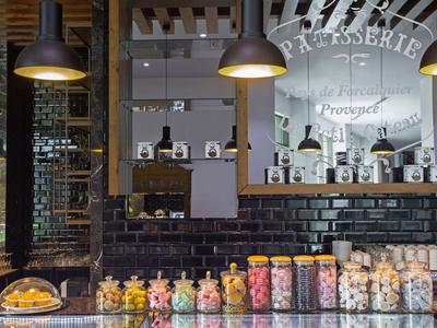 Pasticceria moderna con vetrina in vetro piena di dolci colorati e torta sotto lampade a sospensione.