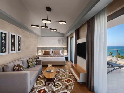 Camera d'hotel moderna con letto, divano e balcone con vista sul mare.