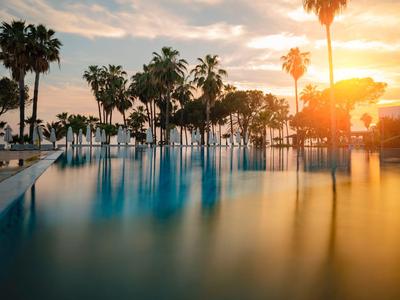 Una piscina tranquilla con palme al tramonto in un resort tropicale.