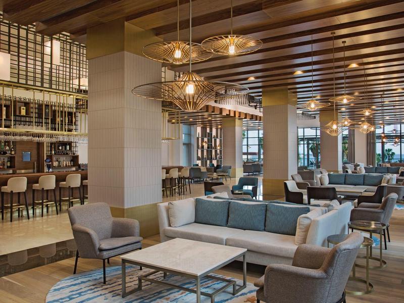 Area lounge moderna dell'hotel con posti a sedere e bar sotto luci calde al soffitto.