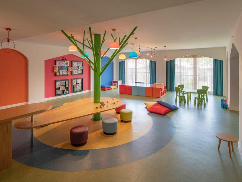 Salotto moderno e colorato con scultura ad albero e cuscini in un hotel.