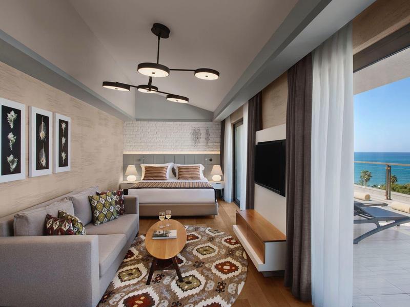 Camera d'hotel moderna con letto, divano e balcone con vista sul mare.