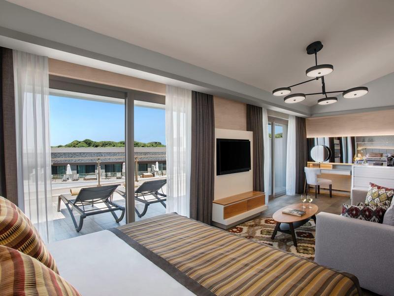 Camera d'hotel moderna con balcone e vista sulla piscina.