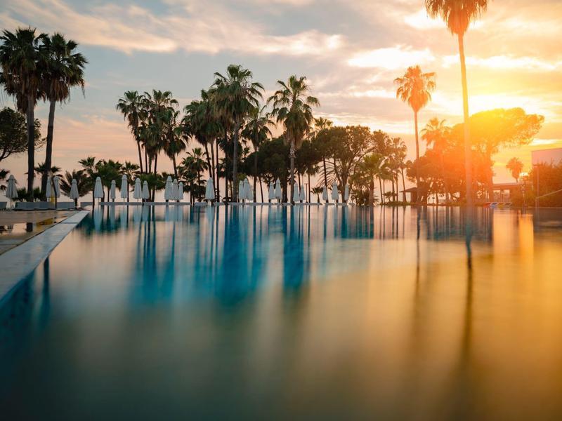 Piscina tranquilla con palme al tramonto in un hotel tropicale.