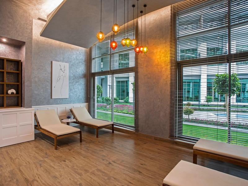 Sala relax moderna con lettini, grandi finestre e luci calde sospese.