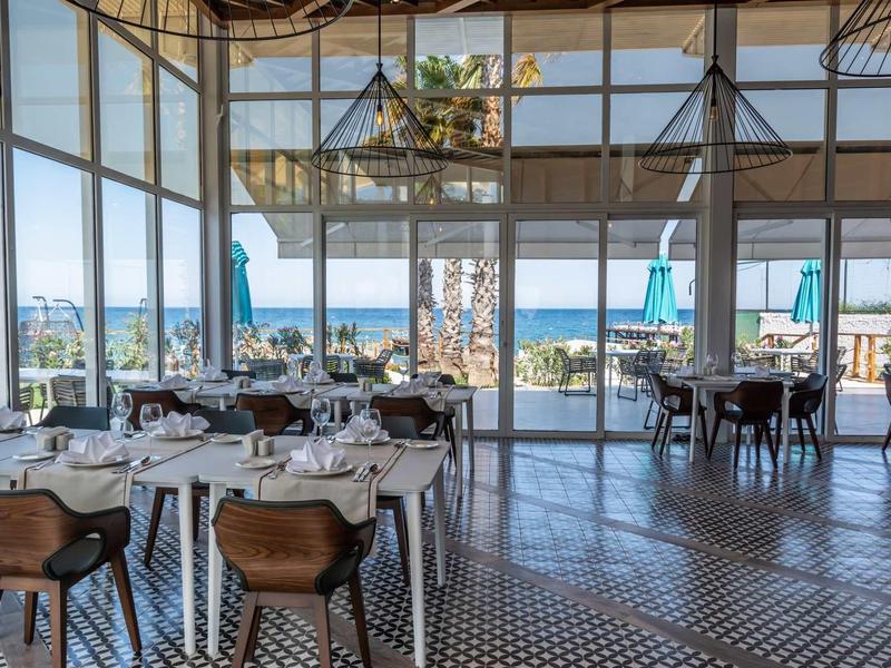 Bright restaurant with large windows, modern design, and sea view.