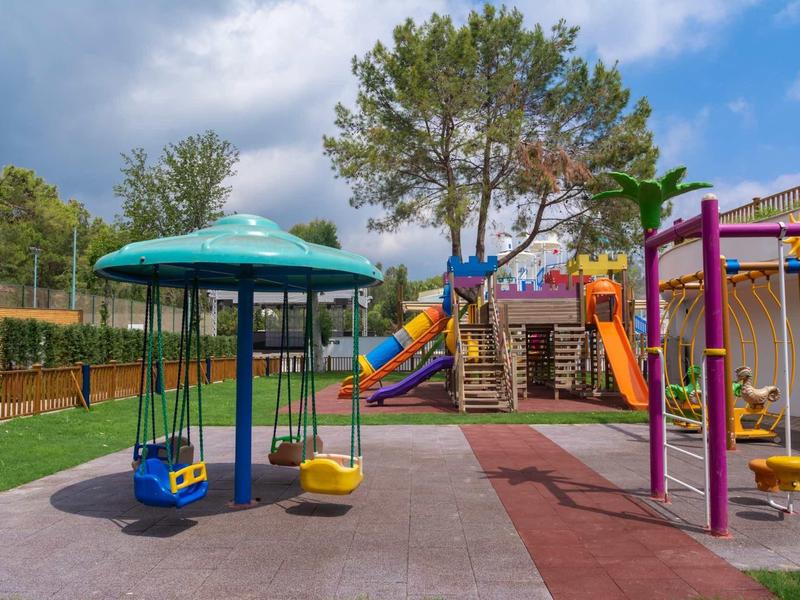 A colorful children's playground with swings, slide, and climbing frame under clear sky.