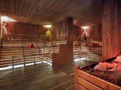 Spacious wooden sauna room with tiered benches and soft warm lighting.