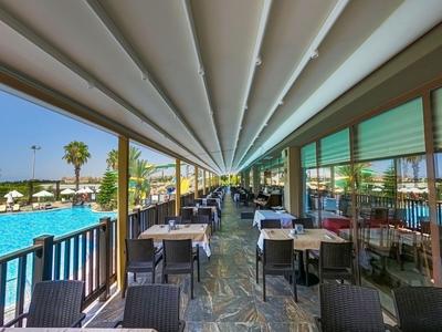 Moderner Speisesaal am Pool mit gedeckten Tischen und Blick auf das Wasser.
