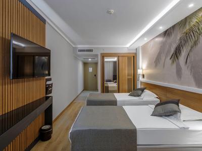Modernes Hotelzimmer mit zwei Betten, Holzakzenten und großem Wandbild mit Palmenmotiv.
