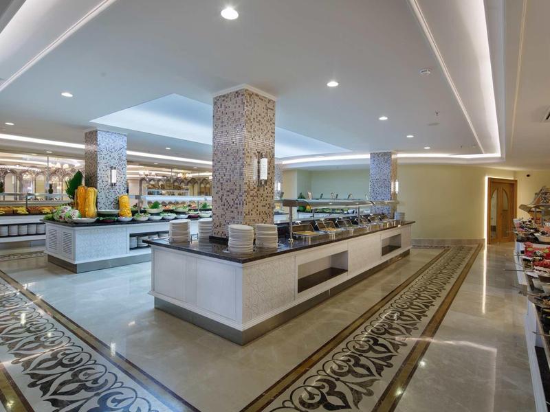 Spacious hotel buffet area with modern design and food stations under bright lighting.