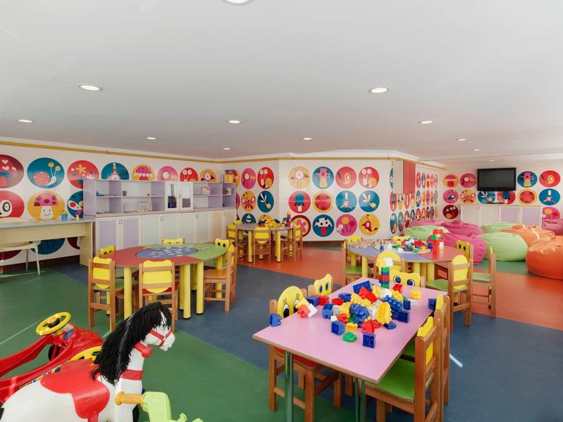 Colorful indoor playroom with toys, tables, and chairs for children.